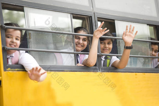 快乐的小学生从校车的窗户挥手