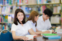 亚洲学生女士微笑和在大学的图书馆看书