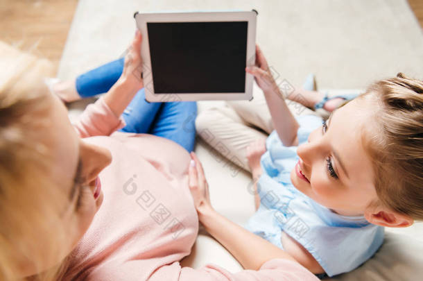 母亲带着女儿使用数字平板电脑 
