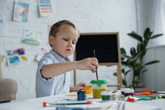 聚焦的小男孩与刷子和绘画画图片独自在家