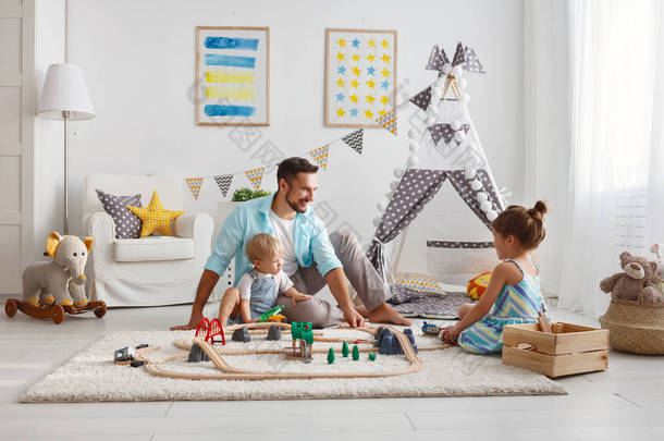 家庭父亲和孩子在游戏室玩玩具铁路
