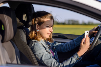 Young female driver reading a text message图片