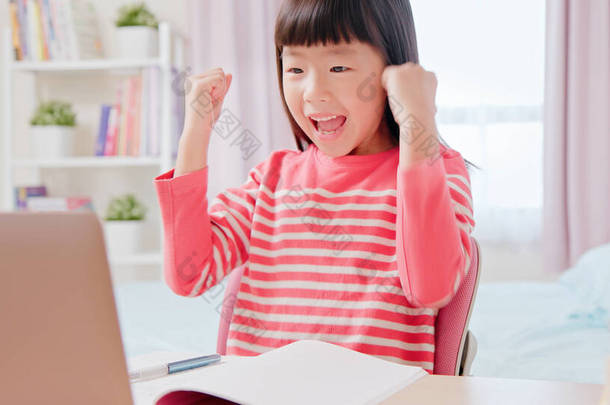 亚洲女学生感到很兴奋，很高兴用笔记本电脑在家里愉快地上网上课