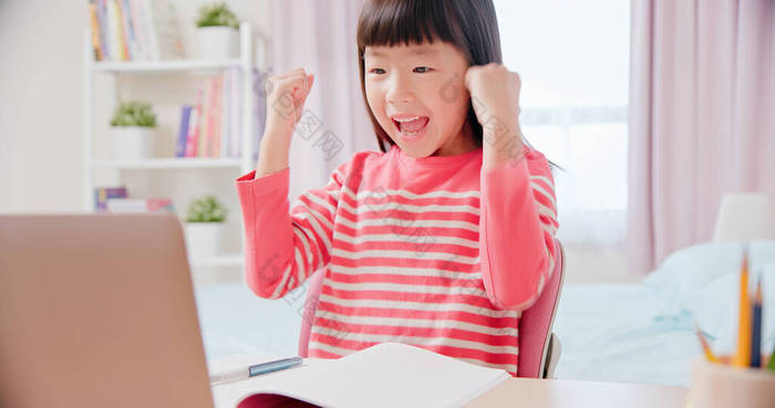 亚洲女学生感到很兴奋，很高兴用笔记本电脑在家里愉快地上网上课