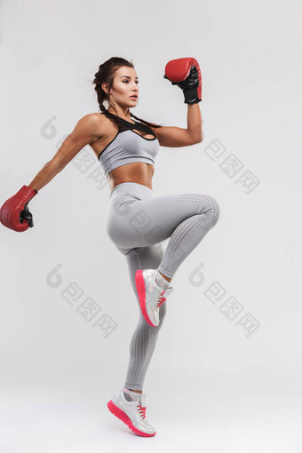 美丽的年轻惊人的强大的运动健身女拳击手姿势孤立在白墙背景做手套练习.图片