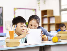 亚洲小学女生和男生在一起使用平板电脑