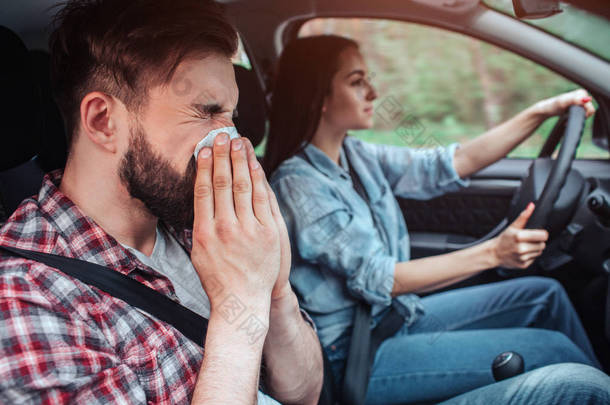 生病的人正在开车。他在餐巾上打喷嚏。女孩在开汽车。她直视前方.