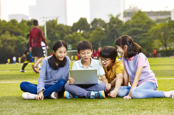 亚洲小学男孩和女孩坐在操场上 gra