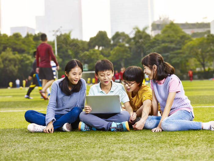 亚洲小学男孩和女孩坐在操场上 gra