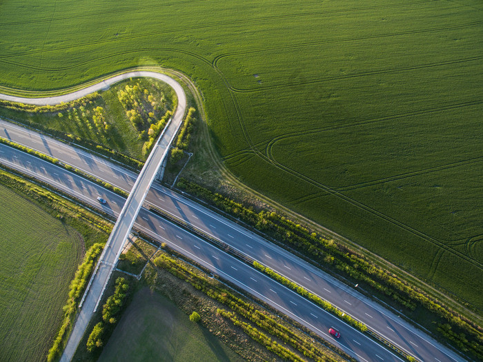 在有汽车的田野中的高速公路的空中景观