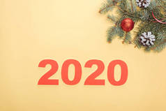 靠近黄底有灌木和球果的圣诞树枝的2020年纸牌号顶部视图