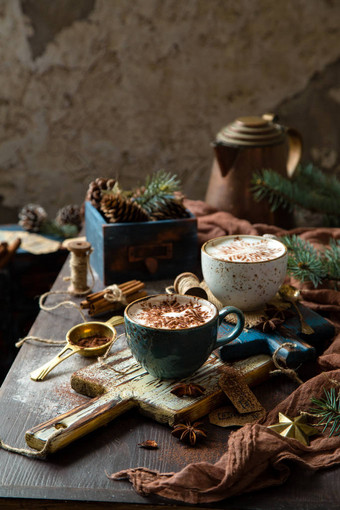 圣诞佳节还有两杯热腾腾的奶油饮料（可可、巧克力、咖啡），上面放着雪花可可饰品，放在带有松木和香料的乡村桌上的木板上图片