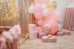 漂亮的粉色装饰，用缎带和蝴蝶结包裹的礼品盒，金光闪闪的背景上的花朵和气球。婚礼或女孩生日宴会装饰品.