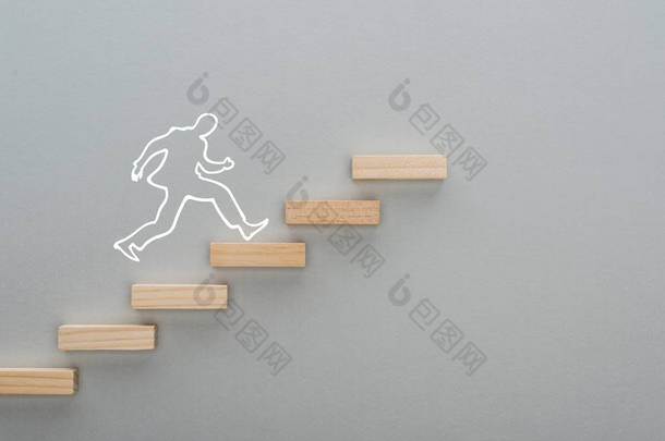 在灰色背景、商业概念<strong>上</strong>象征职业阶梯的木制方块<strong>上</strong>跑步的人的头像