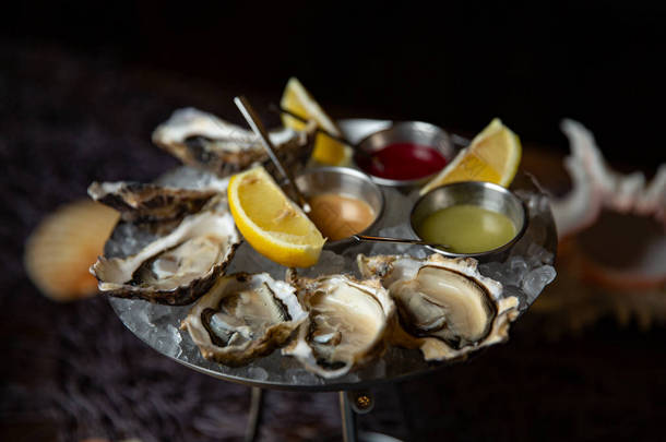 有柠檬的牡蛎<strong>盘子</strong>, 上面有牡蛎和柠檬。新鲜牡蛎特写顶部视图。健康的海洋食品。在餐厅吃牡蛎饭。美味佳肴。海洋食品.