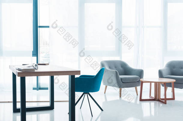 木桌和空舒适的扶手椅在现代办公室内部