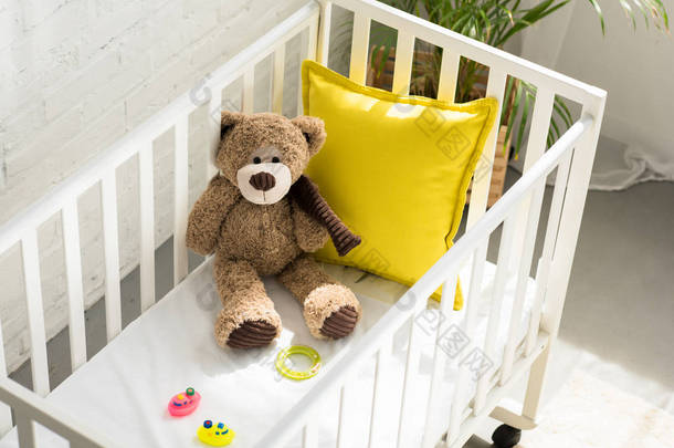 在家婴儿床上的泰迪熊、其他玩具和黄色枕头的高角度<strong>视图</strong>