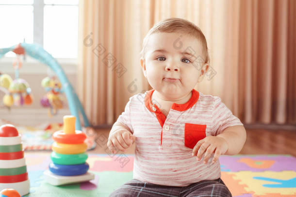 特写肖像可爱可爱的金发白种人<strong>微笑</strong>着孩子的蓝眼睛坐在地板上孩子们的房间。小宝宝在 playmat 玩玩具。早期教育发展