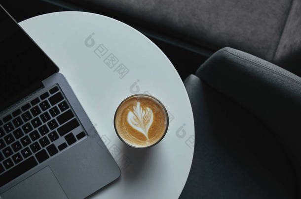 咖啡桌上的咖啡杯和笔记本电脑的顶部视图 