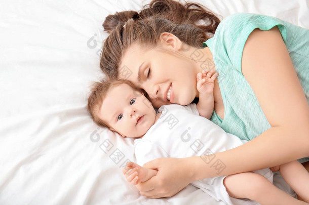 年轻的<strong>母</strong>亲和可爱的<strong>婴儿</strong>在家里的床上