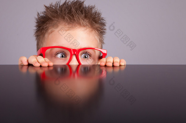 cute boy hiding behind a table