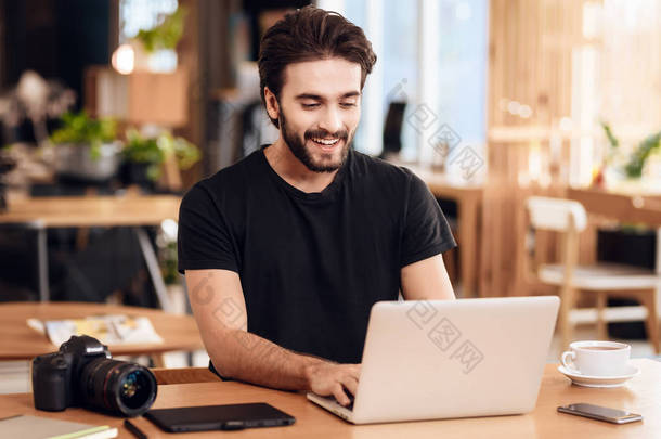 自由职业者胡子男子打字在笔记本电脑坐在办公桌上.