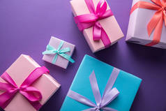 彩色礼品盒顶视图，内附彩带和紫色背景的蝴蝶结