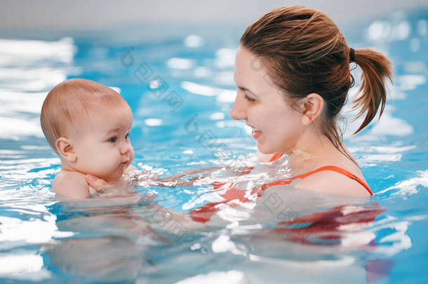 白种白人母亲训练她的新生婴儿在游泳池里漂浮。婴儿在水中潜水。<strong>健康</strong>积极的生活方式。<strong>家庭</strong>活动与早期发展观
