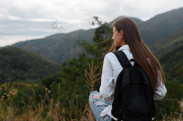 在山的背景下背包的年轻女孩