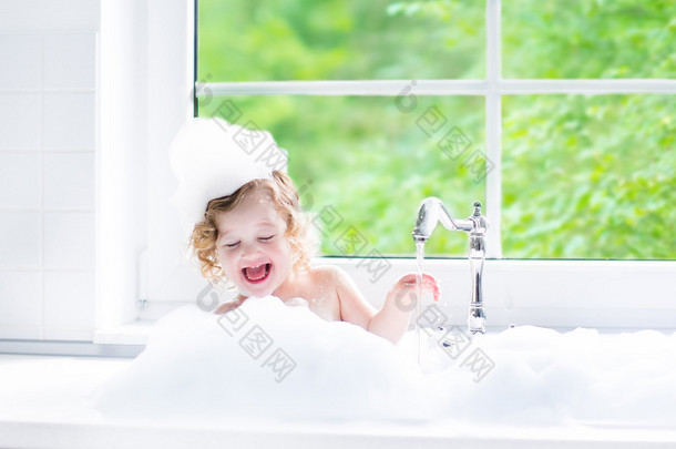 Baby girl taking bath with foam