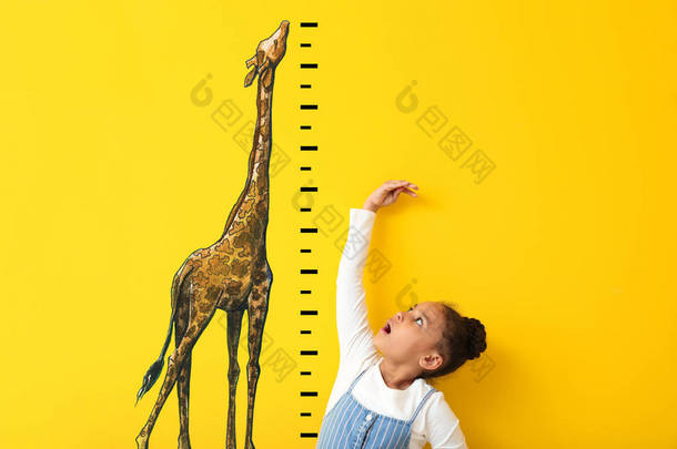 惊讶的非洲裔美国女孩测量<strong>高度</strong>接近彩色墙与绘制长颈鹿