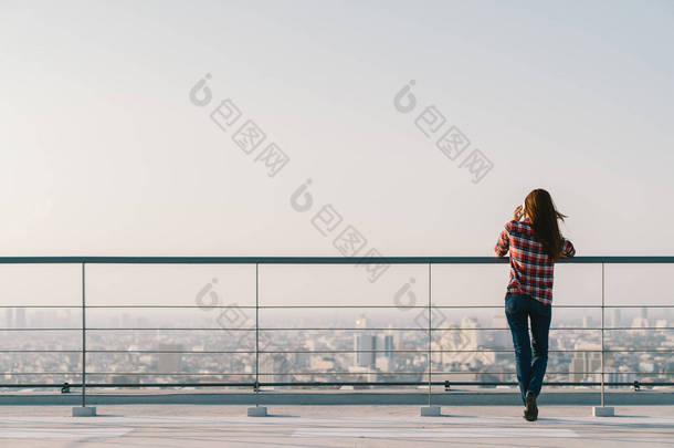 在夕阳与副本空间、 通信或寂寞的人概念在屋顶使用移动电话的女人