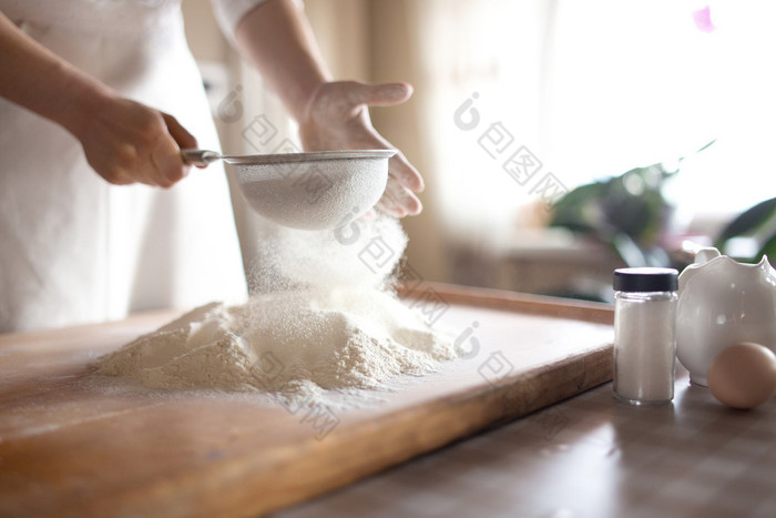 面粉筛入碗在厨房里的年轻女子 厨房做饭