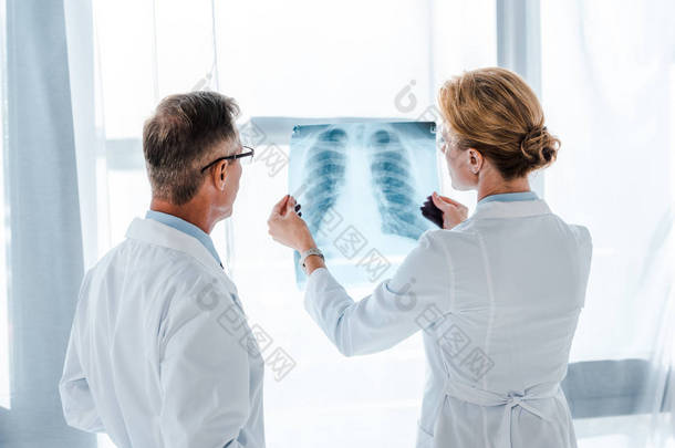 戴眼镜的医生在同事手中看X光片 
