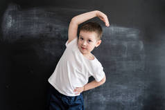 小男孩在黑板边做运动健身操。年轻的运动员。2019日历创意设计理念