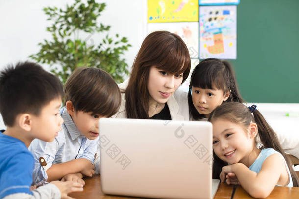 孩子们看着笔记本电脑旁边的老师