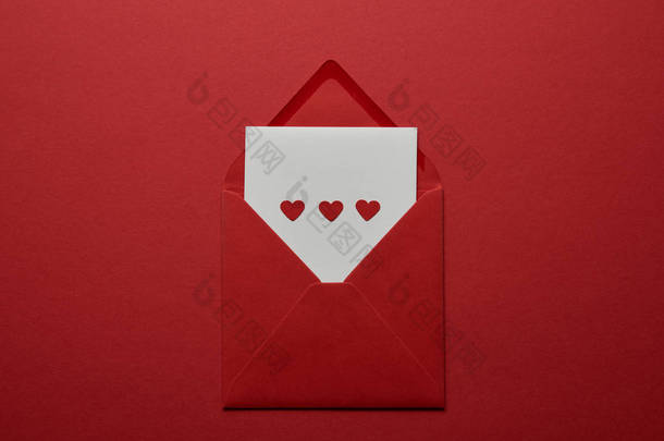 白色信件的顶部看法与心脏在信封在红色<strong>背景</strong>