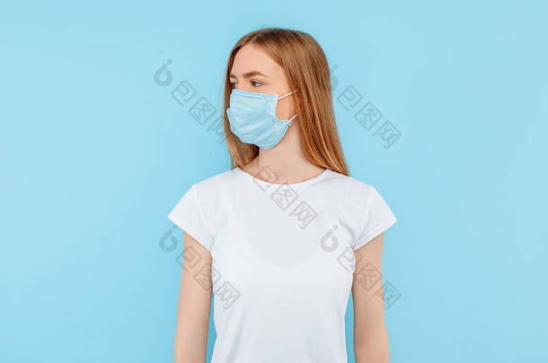 保护自己免受<strong>传染病</strong>的侵袭，考拉威斯。一个年轻的女孩戴着一个卫生面具来防止感染，空气传播的呼吸道疾病。在蓝色背景上隔离的闭合演播室镜头