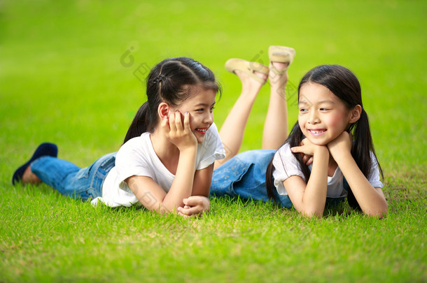 躺在绿草地上的两个<strong>小</strong>的亚洲<strong>女孩</strong>