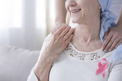 特写微笑的老年妇女以粉红色丝带作为抗击乳腺癌的标志