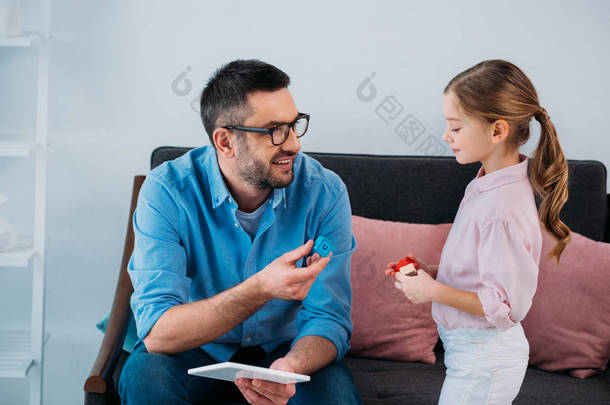 微笑的父亲和女儿用五颜六色的块在手在家