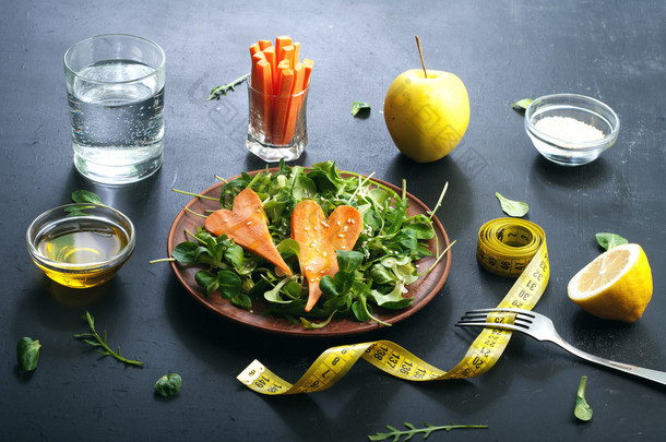 Concept diet food. Salad with arugula, leaf mash and carrots on a dark background. Vegetarian health
