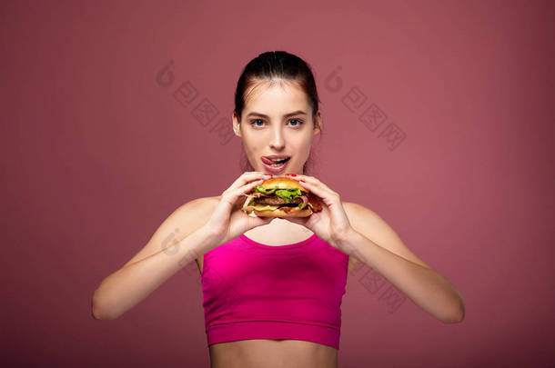 Athletic white girl with a beautiful body eats a burger.