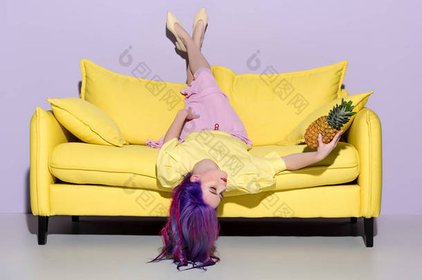 美丽的年轻女子躺在<strong>黄色</strong>的沙发上与菠萝