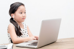 可爱的女生女孩与桌上的笔记本电脑电脑 