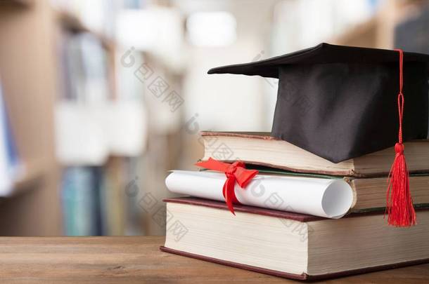 <strong>毕业</strong>帽子和堆栈的木桌子上的书