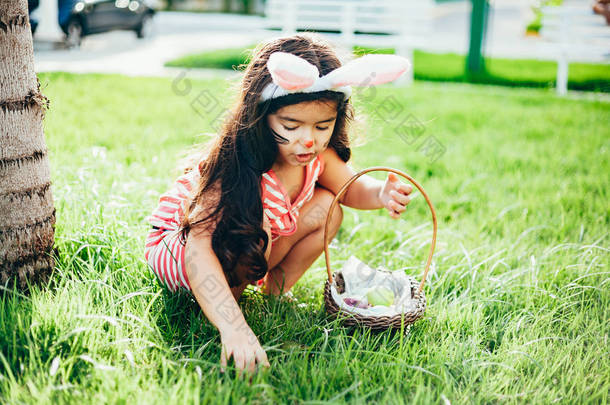 可爱的小女孩与兔子耳朵和<strong>复活节彩蛋</strong>篮子在花园里。寻找<strong>复活节彩蛋</strong>