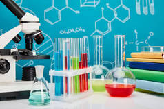 带蓝色背景、分子结构的彩色液体的显微镜、书籍、玻璃管和瓶