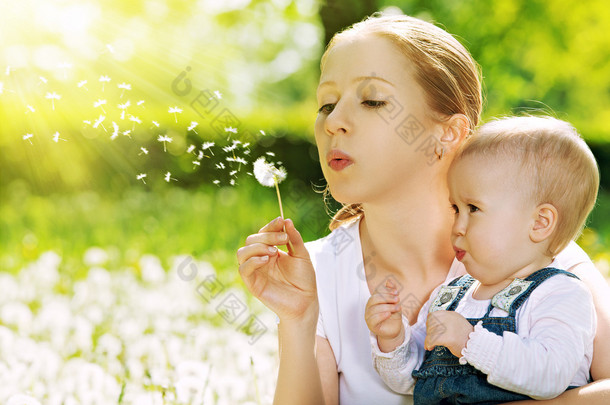 幸福的家庭。母亲和婴儿女孩吹上一朵蒲公英的花