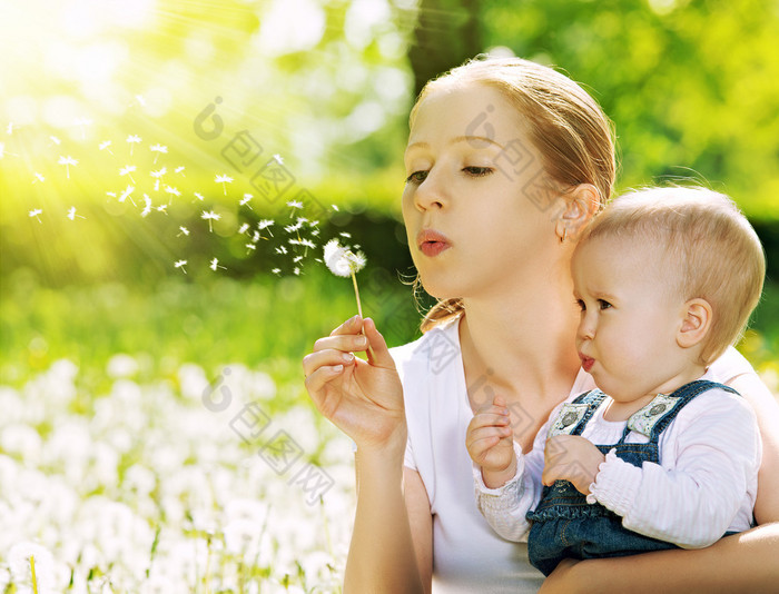 幸福的家庭。母亲和婴儿女孩吹上一朵蒲公英的花